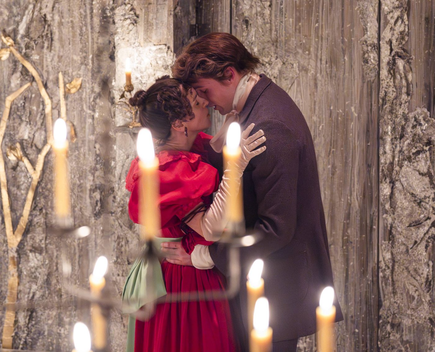 Natalie Klamar as Natalya and Stuart Thompson as Andrei in Three Sisters. Natalya's hands are on Andrei's shoulders and his hands are on her waist. They look like they are about to kiss.