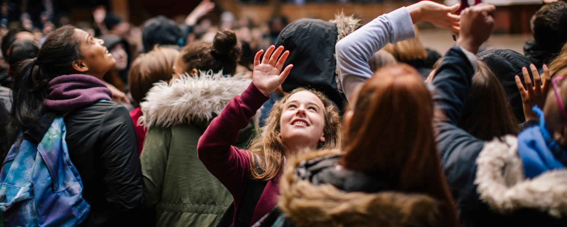 A schoolgirl reaches into the air during a show to catch a piece of confetti