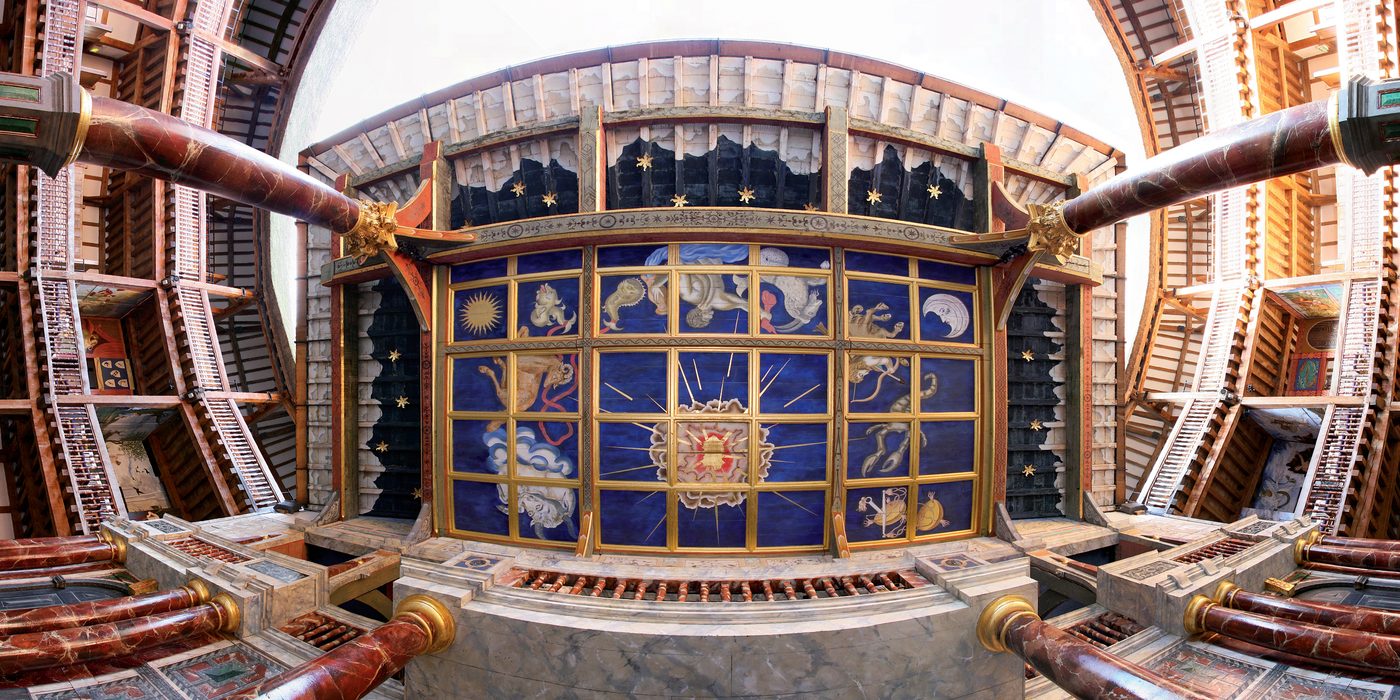 A shot directly underneath the Heavens of the Globe Theatre, looking up at a painted blue ceiling with stars, sun, moon and signs of the zodiac.