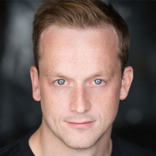 This is a headshot of Jolyon Coy looking directly to camera.