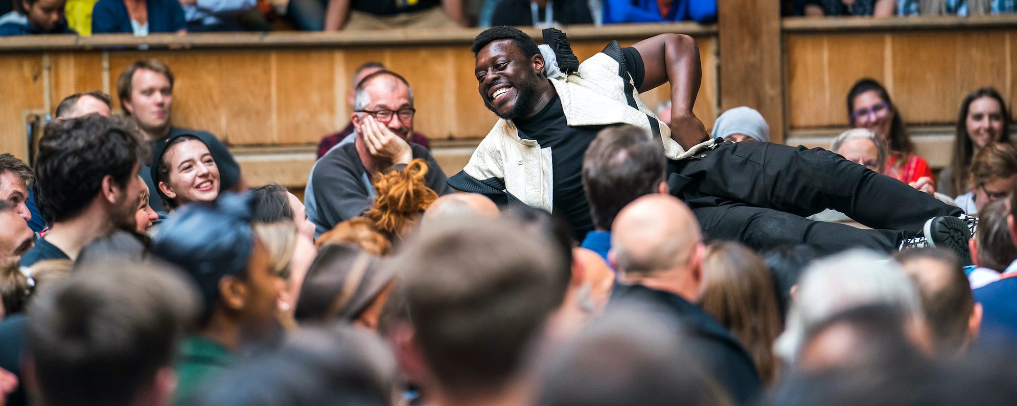 An actor lies on the edge of a stage performing to the audience