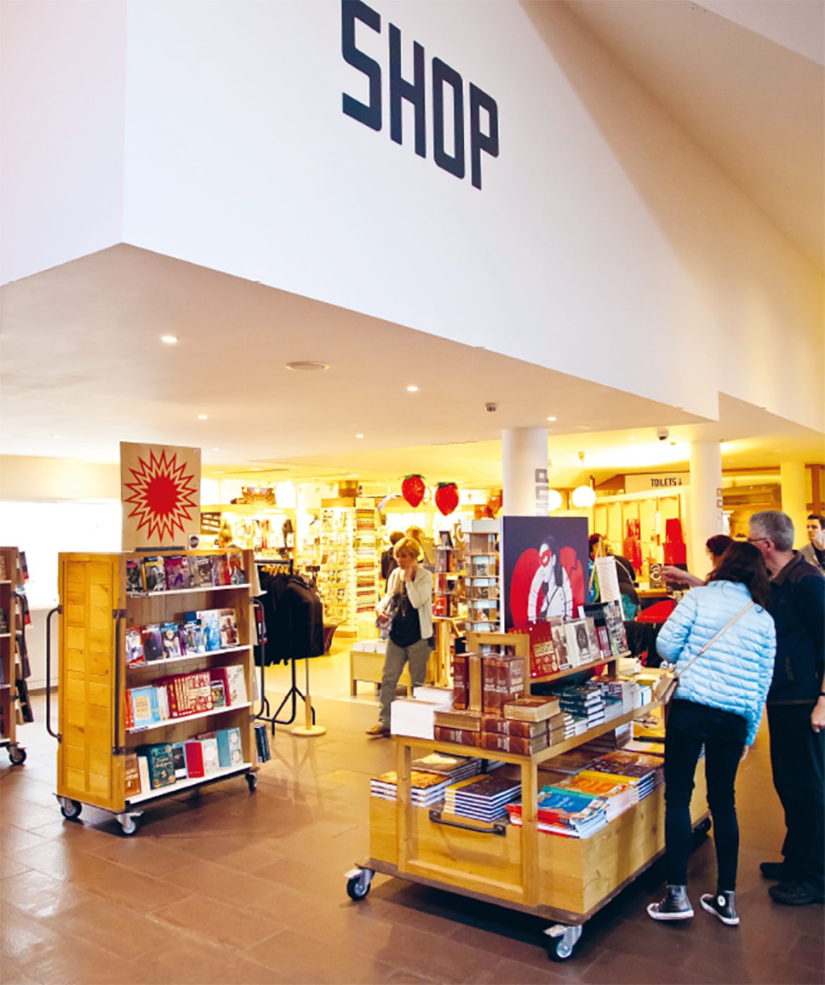 Customers browse a display of books in a shop.
