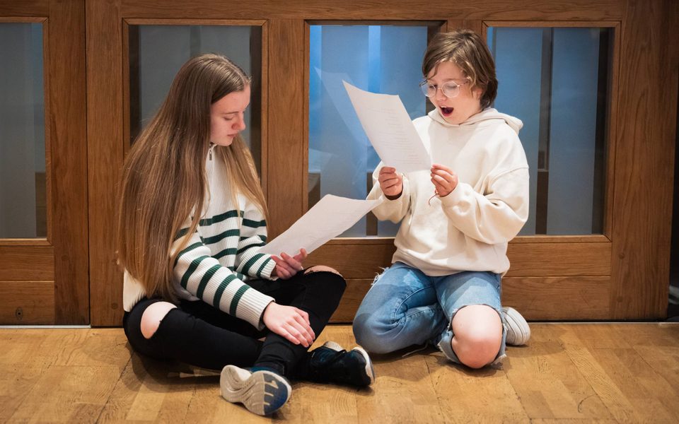 Two young people reading from scripts during a family drama workshop.