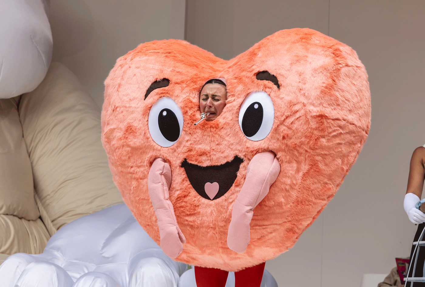 Eloise Secker as Grumio wearing a giant heart costume blowing a mini flute. Photography by Ellie Kurttz.